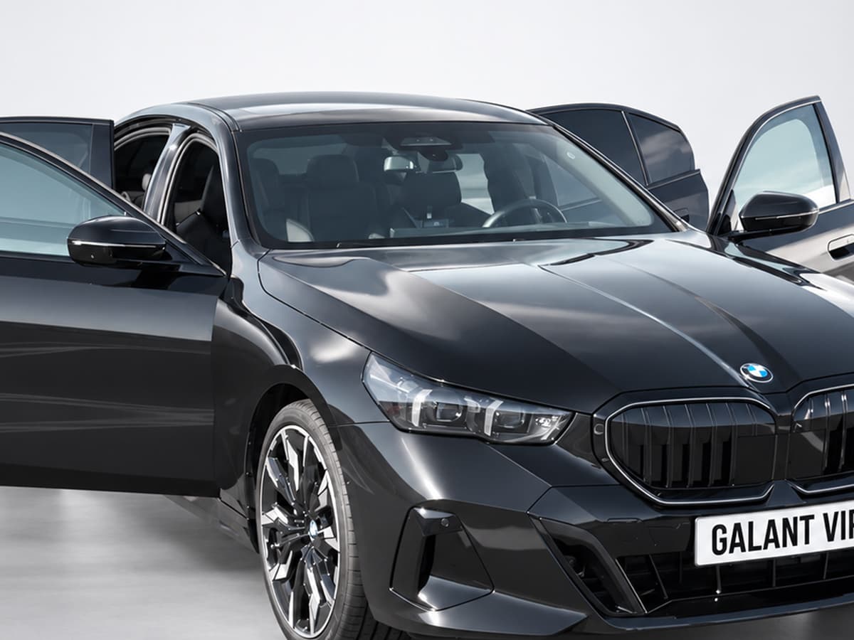 BMW Seria 5 negru Galant VIP, văzut din față și lateral, cu portierele deschise.